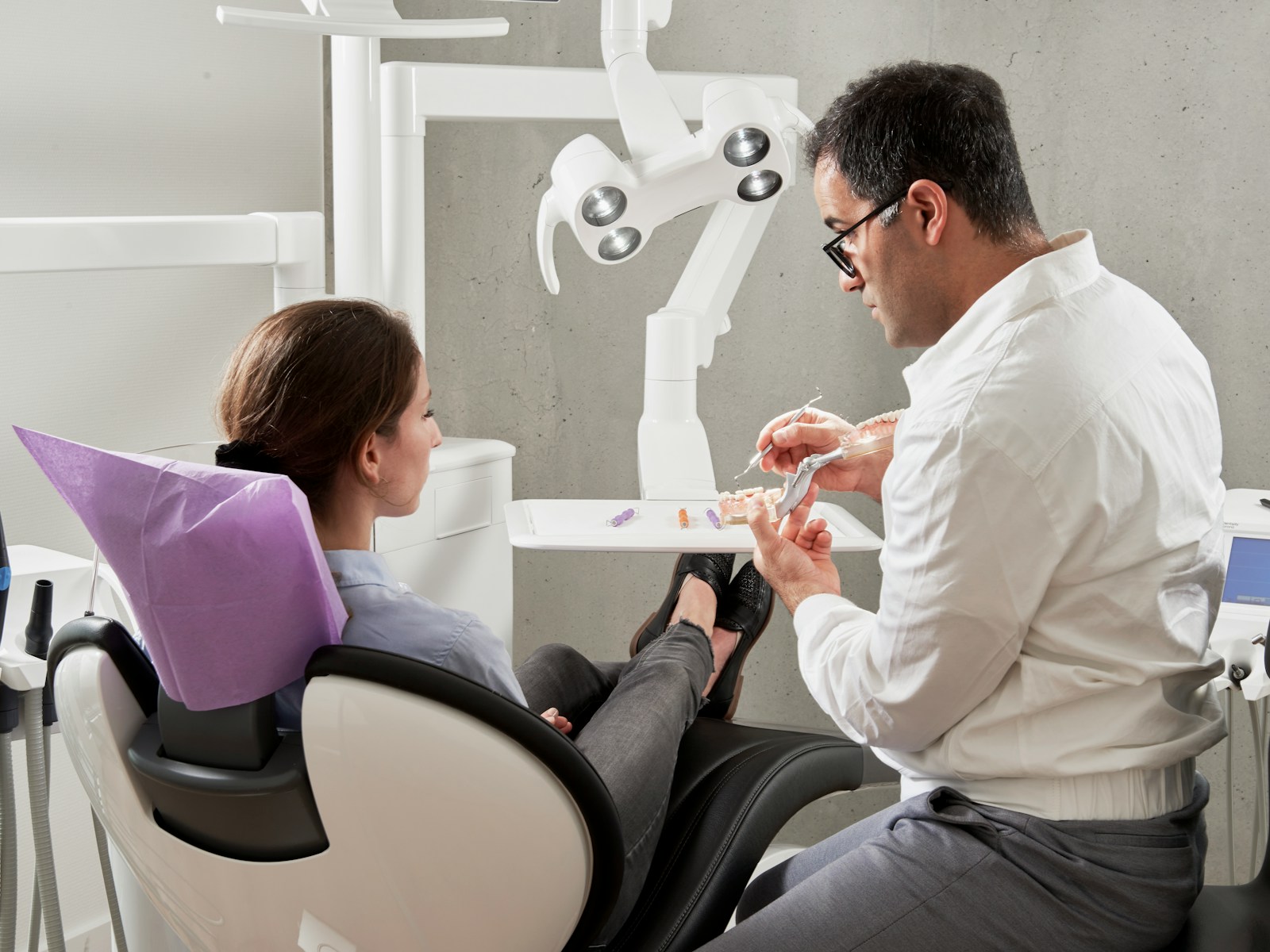 man in white dress shirt sitting on black office rolling chair, dental